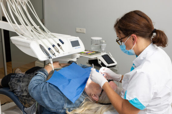 Patiënt op stoel met handen van behandelaar bij de mond - Dental Clinics Eindhoven