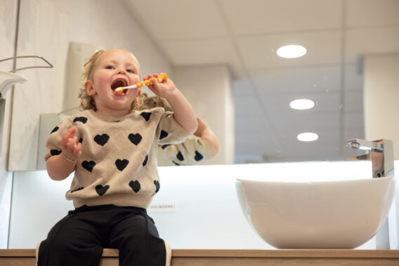 A toddler brushing her teeth at the brushing station at Dental Clinics Reeshof