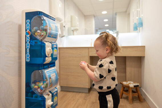 A toddler taking something out of a toy vending machine Dental Clinics Reeshof
