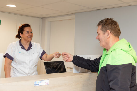 Photo of a patient handing something to the receptionist at the front desk at Dental Clinics Reeshof