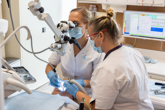 Tandarts kijkt door microscoop tijdens behandeling