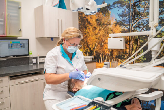 Behandelaar doet behandeling bij patiënt in stoel Dental Clinics Gieten