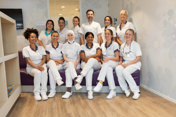 Teamfoto op paarse bank Dental Clinics Haarlem Zijlweg
