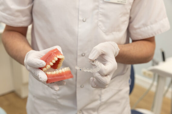 Handen van tandarts met een gebit in de ene hand en een aligner in de andere hand Dental Clinics Purmerend Weidevenne