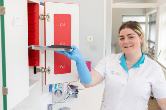 Omloopassistent doet een dienblad in de schoon/vies-kast Dental Clinics Purmerend Weidevenne