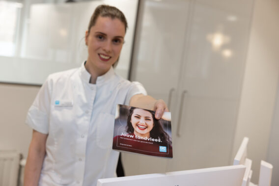 Receptionist met folder 'Jouw tandvlees.'