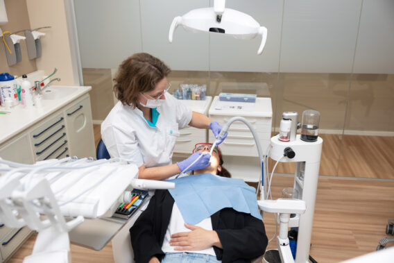 Behandelaar behandelt patiënt in stoel met instrumenten en spatbril op Dental Clinics Hattem