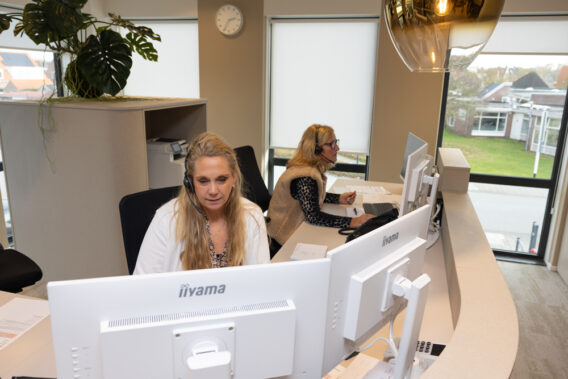 Receptiemedewerkers achter de balie kijkend naar de computers Dental Clinics Hattem