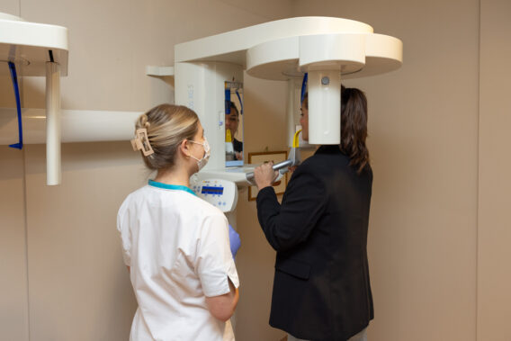 Tandartsassistent staat naast röntgenapparaat en helpt patiënt te positioneren Dental Clinics Hattem