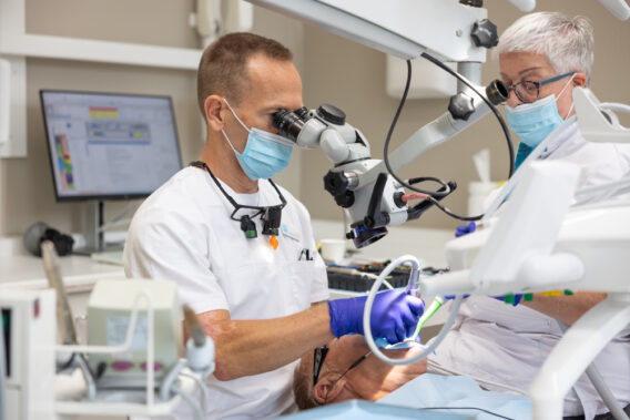 Tandarts kijkt door microscoop tijdens behandeling bij Dental Clinics Steenbergen
