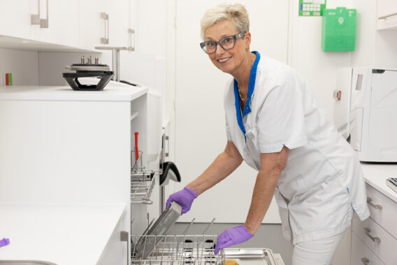 Sterilization assistant places dirty instruments in the dishwasher at Dental Clinics