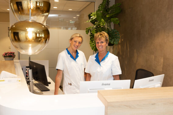 Two assistants behind the reception desk at Dental Clinics